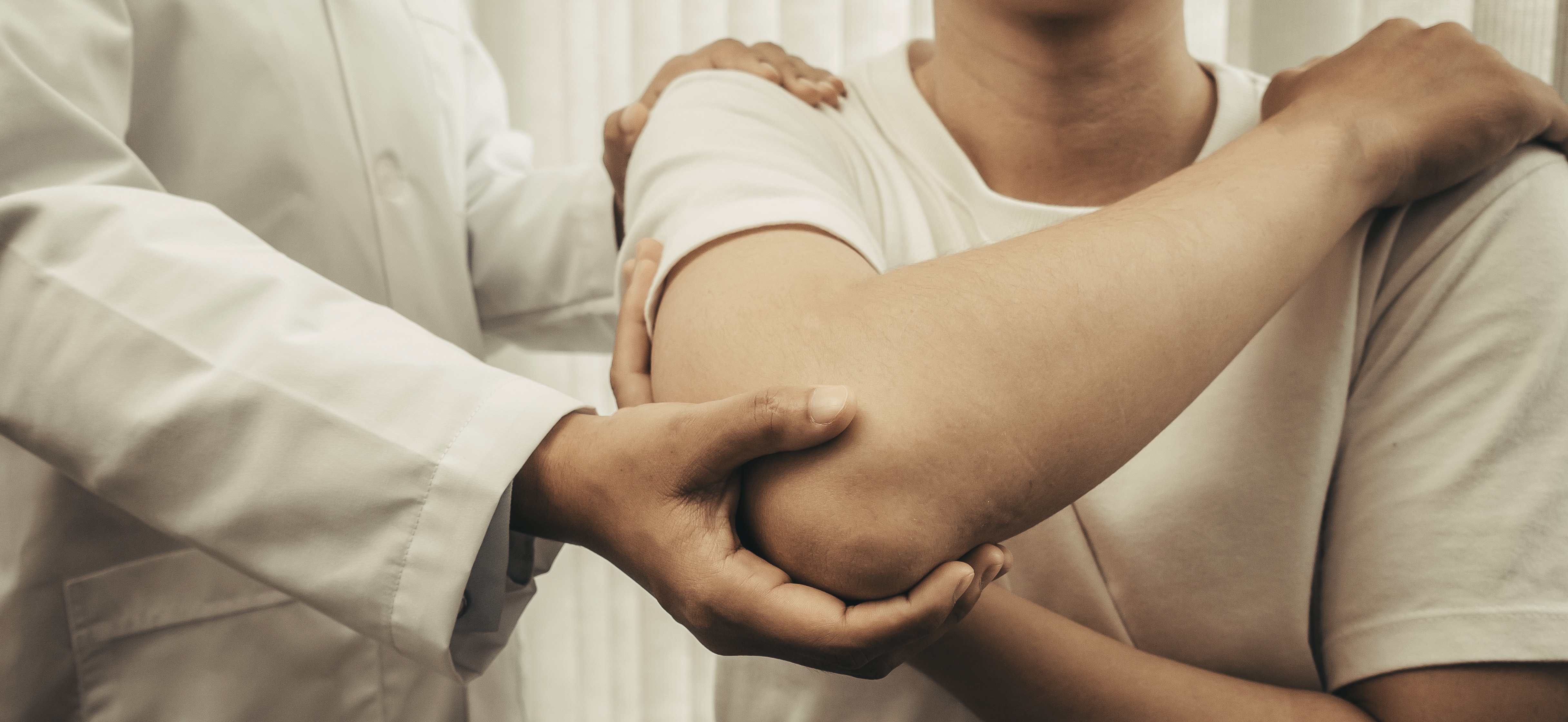 Physical therapist supporting a patient's elbow during a manual assessment