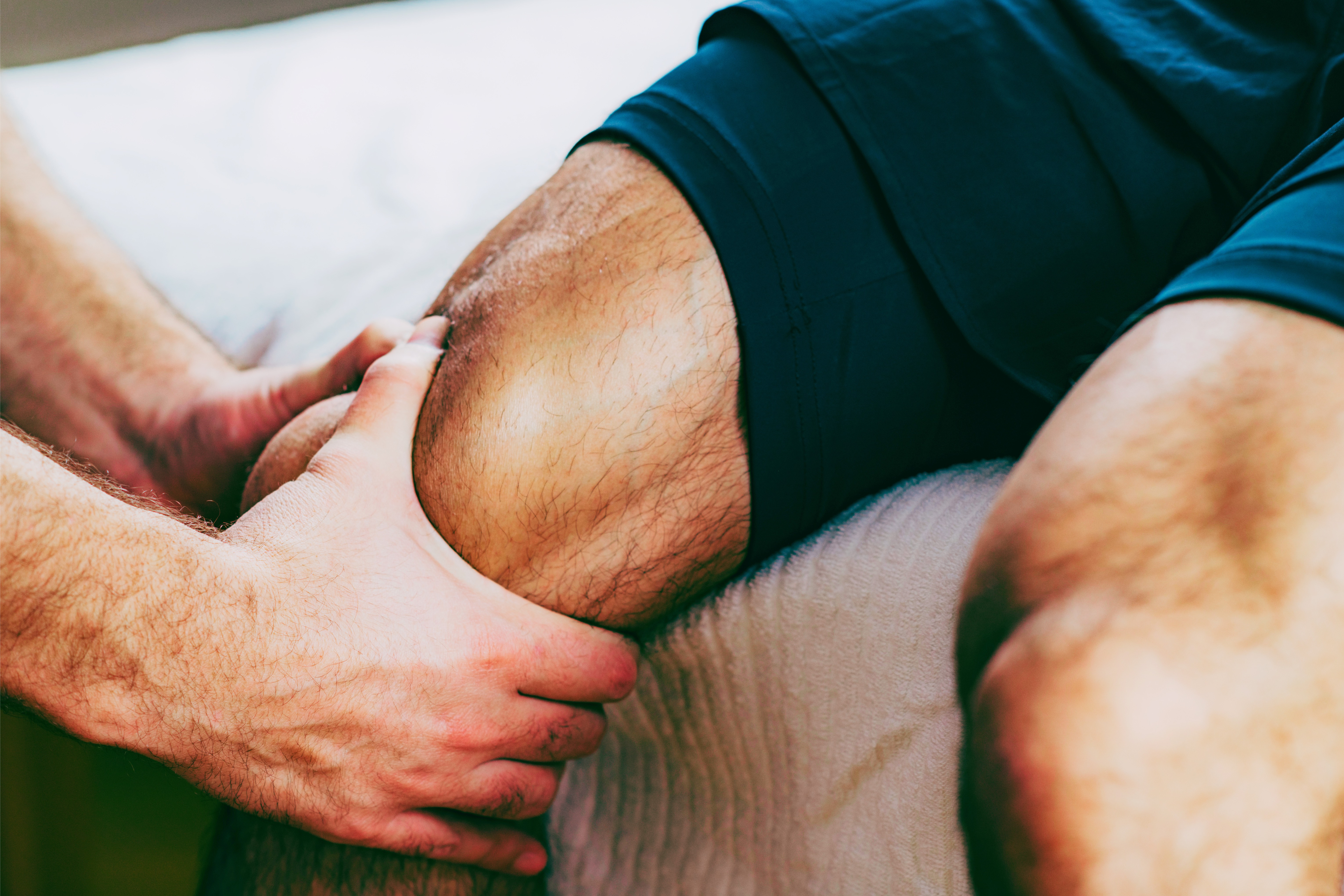 Therapist applying hands-on pressure to a patient's quadriceps
